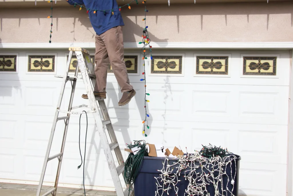 image of a person installing outdoor holiday lights over a garage gate, safety blog