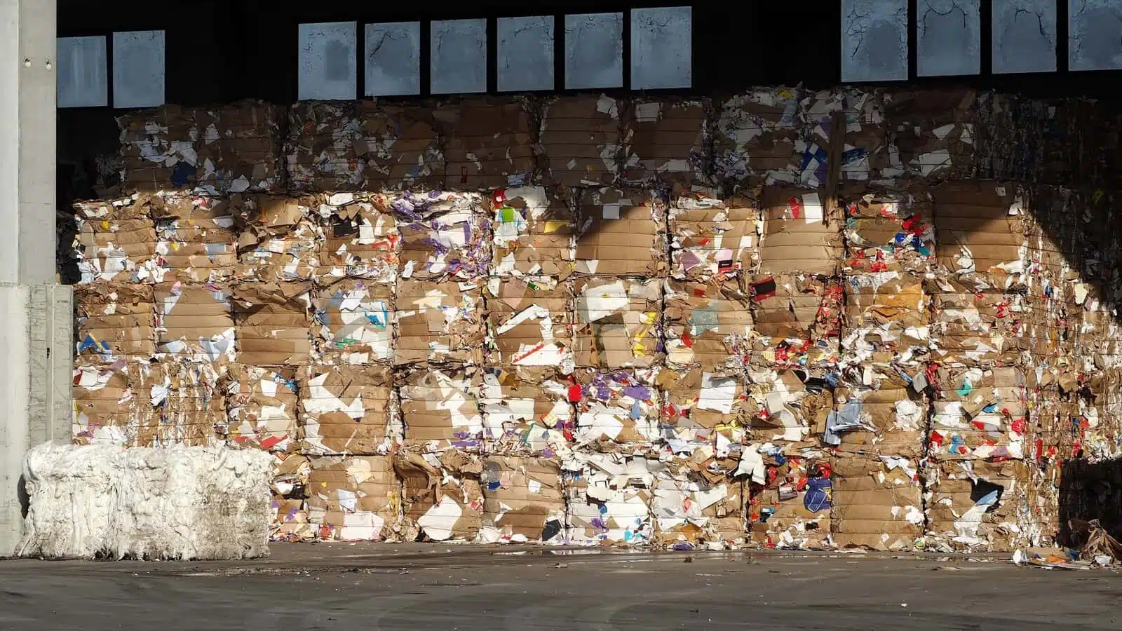 lined up stacks of cardboard and waste paper in a recycling plant storage